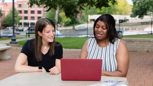 Students talking in front of a laptop